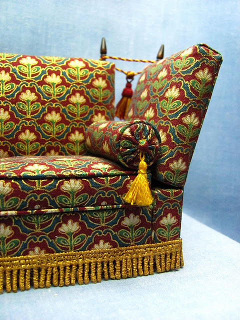 Close up of the 1:12 scale knole sofa replica of the 17th century design, tassled and knobbed.  It was originally used not as comfortable sofa but as a formal throne on which the monarch would have sat to receive visitors.  This replica is created in 1/12 scale by CDHM Artisan Kris Compas of 1 Inch Minis